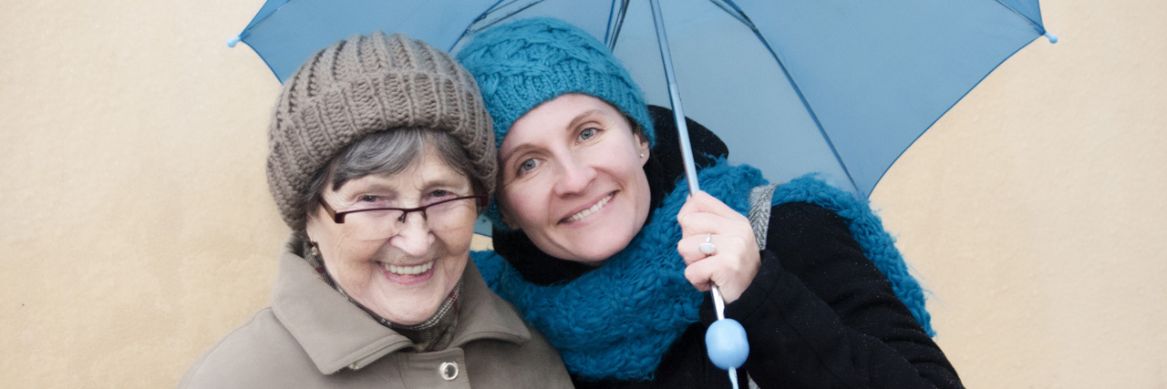 Two women holding an umbrella.